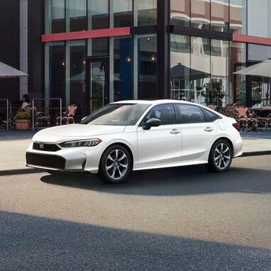 2027 Honda Civic Sedan Sport Touring Hybrid in Platinum White Pearl front three-quarter view parked (Compact Sedan)